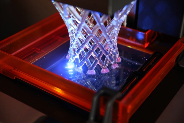 The build platform is gradually raised as layers of resin are cured by the light, forming the final object.